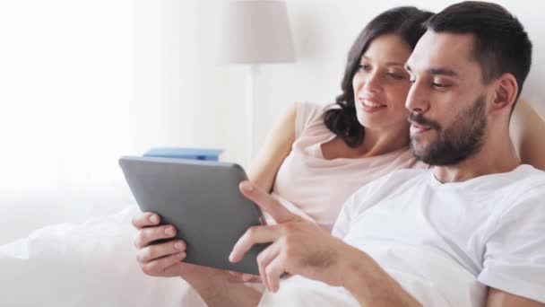 Lachende echtpaar in bed met tablet pc-computer — Stockvideo