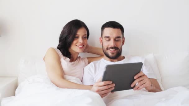 Улыбающаяся пара в постели с планшетным компьютером — стоковое видео