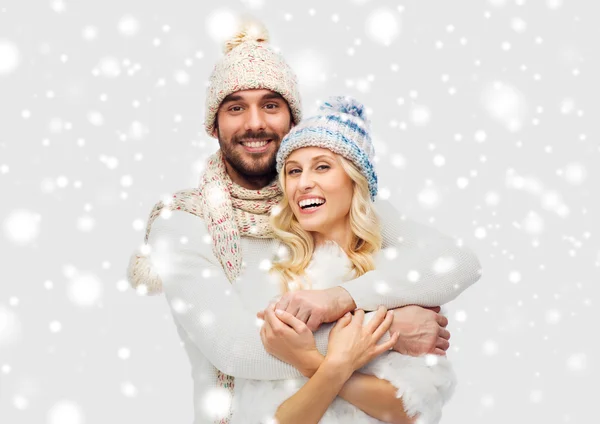 Усміхнена пара в зимовому одязі обіймається над снігом — стокове фото