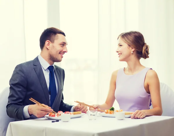 Sorrindo casal comer sushi no restaurante — Fotografia de Stock