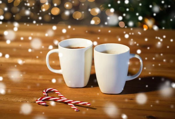 Рождественские конфетки и чашки на деревянном столе — стоковое фото