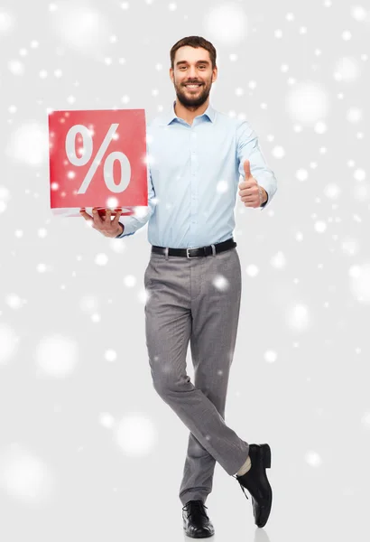 Hombre sonriente con signo de porcentaje rojo sobre la nieve — Foto de Stock