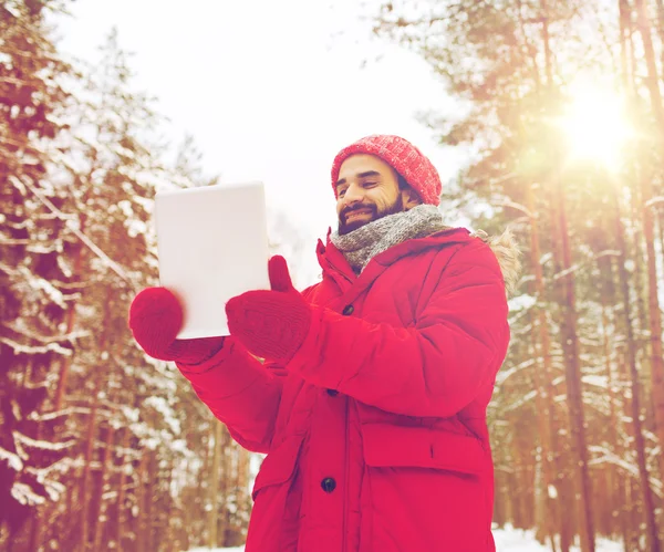 Счастливый человек с планшетным компьютером в зимнем лесу — стоковое фото