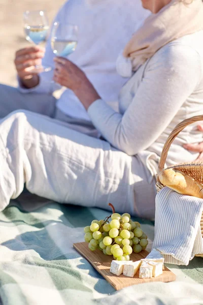 Happy senior couple having picnic on summer beach — Stock Photo, Image