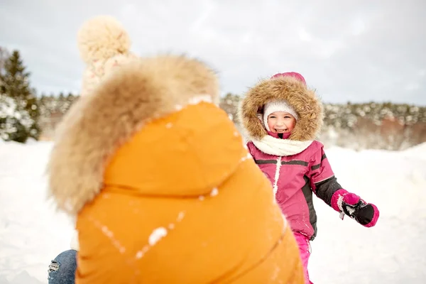 Счастливая семья в зимней одежде играет на открытом воздухе — стоковое фото