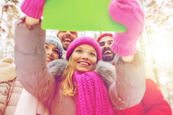 Amigos sorridentes com tablet pc na floresta de inverno — Fotografia de Stock