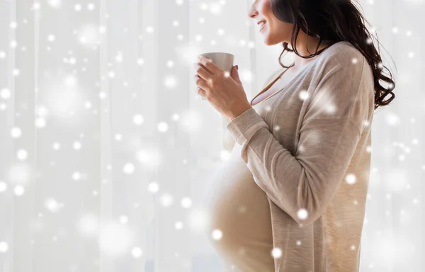 Primer plano de la mujer embarazada con taza de té en la ventana — Foto de Stock