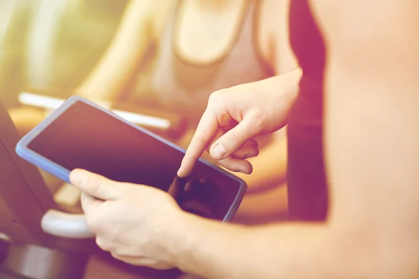 close up of trainer hands with tablet pc in gym