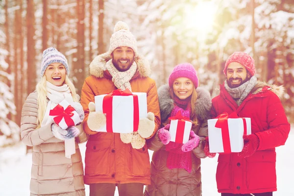 Gelukkige vrienden met gift boxes in winter forest — Stockfoto