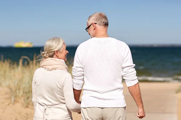 Feliz pareja de ancianos tomados de la mano en verano playa — Foto de Stock