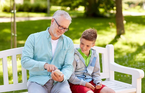 Старик и мальчик со смартфонами в летнем парке — стоковое фото
