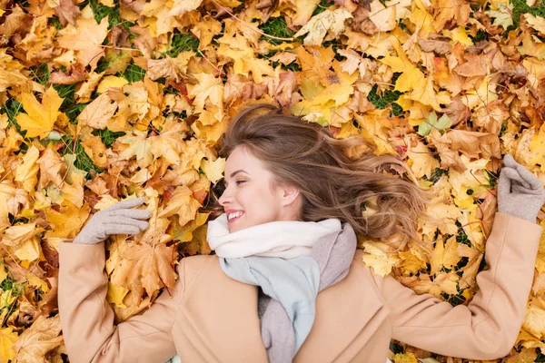 Belle femme heureuse allongée sur des feuilles d'automne — Photo