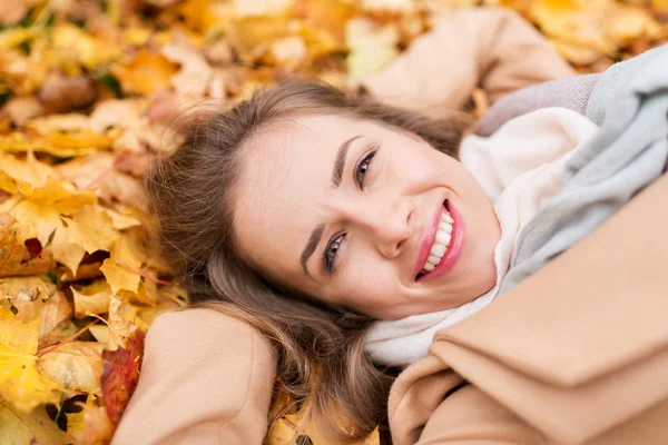Hermosa mujer feliz acostada en hojas de otoño —  Fotos de Stock