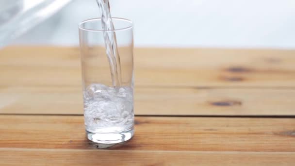 Água derramando em vidro na mesa de madeira — Vídeo de Stock