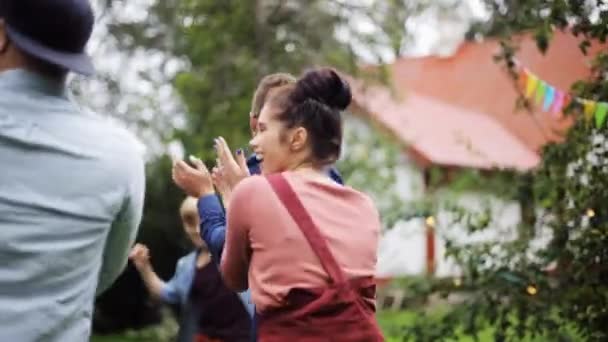 Счастливые друзья танцуют на летней вечеринке в саду — стоковое видео