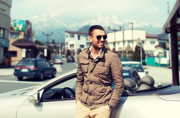 Homem feliz perto de carro cabriolet sobre a cidade no japão — Fotografia de Stock