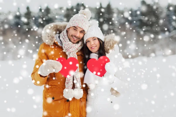 คู่รักที่มีความสุขที่มีหัวใจสีแดงเหนือภูมิทัศน์ฤดูหนาว — ภาพถ่ายสต็อก