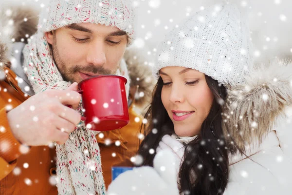 Šťastný pár s čajové šálky nad zimní krajina — Stock fotografie