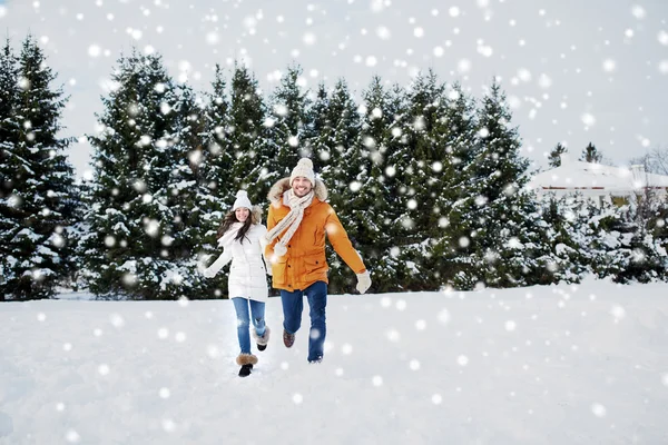 Casal feliz correndo na neve de inverno — Fotografia de Stock