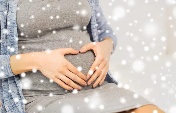 Close-up da barriga da mulher grávida e forma do coração — Fotografia de Stock