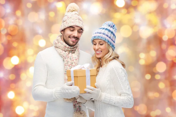 Smiling couple in winter clothes with gift box — Stock Photo, Image