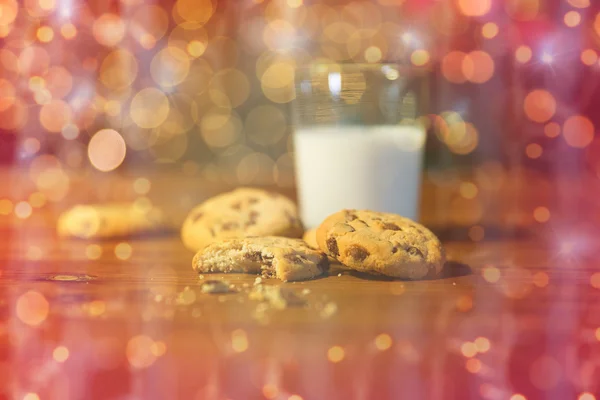 Närbild på kakor och mjölk över julbelysning — Stockfoto
