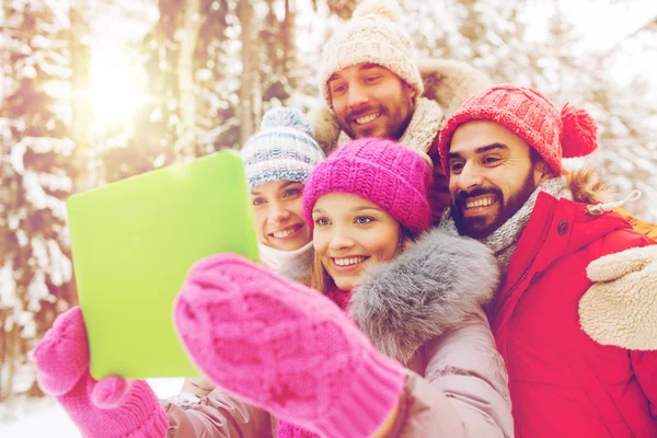 Lachende vrienden met tablet pc in winter forest — Stockfoto