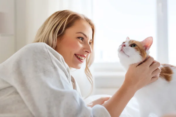 Glad ung kvinna med katt i sängen hemma — Stockfoto