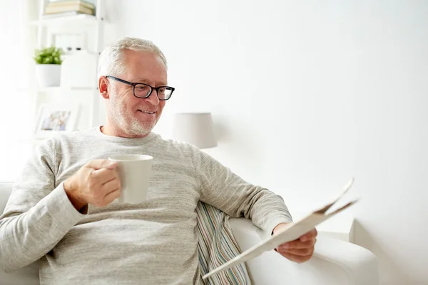 Homem sênior em óculos lendo jornal em casa — Fotografia de Stock