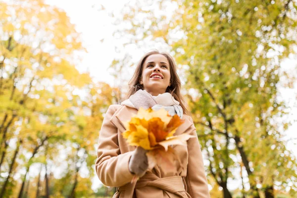 Schöne Frau mit Ahornblättern im Herbstpark — Stockfoto