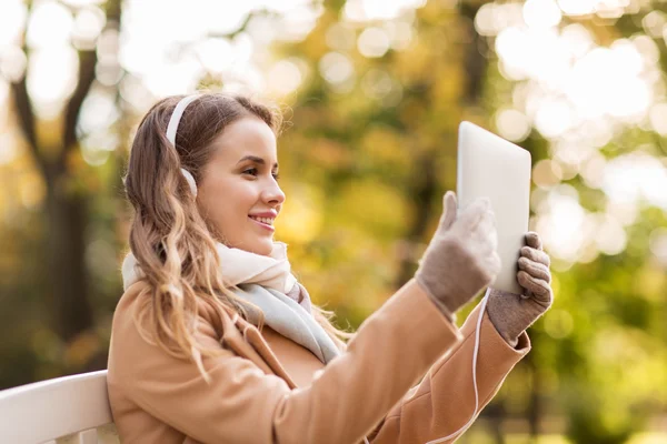 Frau mit Tablet-PC und Kopfhörer im Herbstpark — Stockfoto