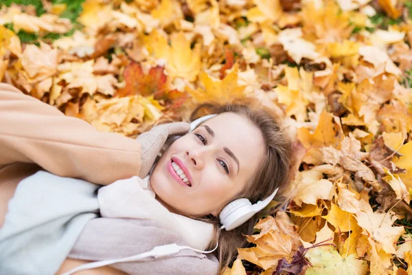 Femme avec écouteurs écoutant de la musique en automne — Photo