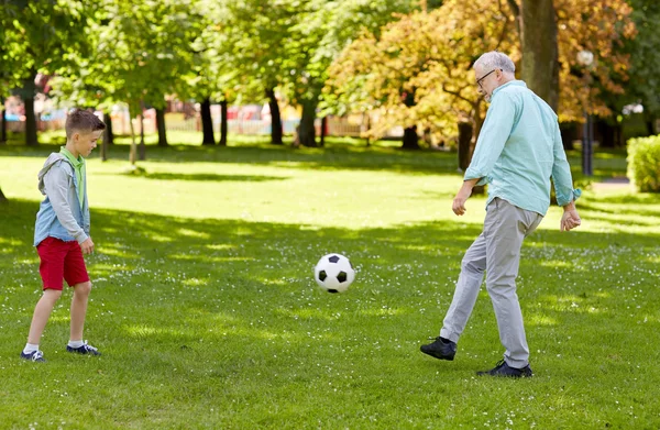 Velho homem e menino jogando futebol no parque de verão — Fotografia de Stock