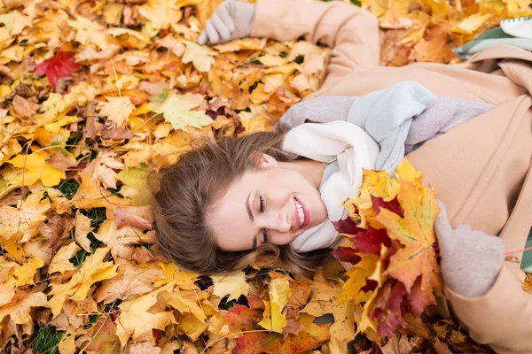 Красива щаслива жінка лежить на осінньому листі — стокове фото