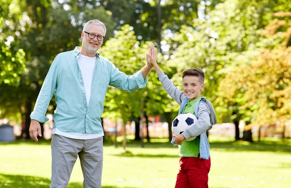 Yaşlı adam ve çocuk futbol topu çak bir beşlik yapma ile — Stok fotoğraf