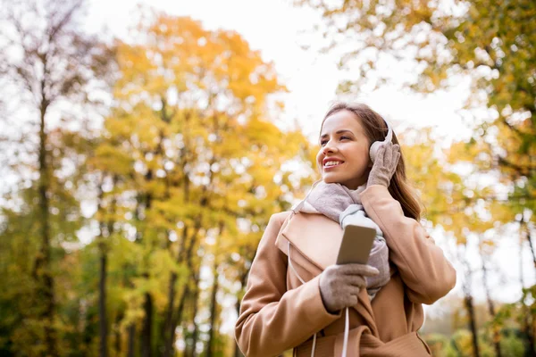 Akıllı telefon ve kulaklık sonbahar Park kadın ile — Stok fotoğraf
