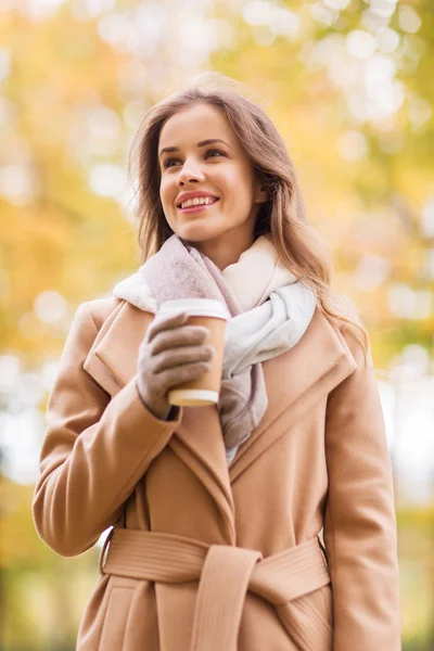 Счастливая молодая женщина пьет кофе в осеннем парке — стоковое фото