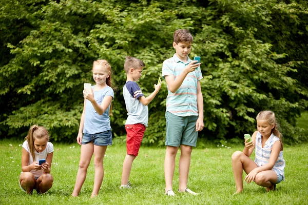 Enfants avec smartphones jouer au jeu dans le parc d'été — Photo