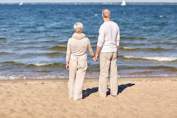 Feliz pareja de ancianos cogidos de la mano verano playa — Foto de Stock