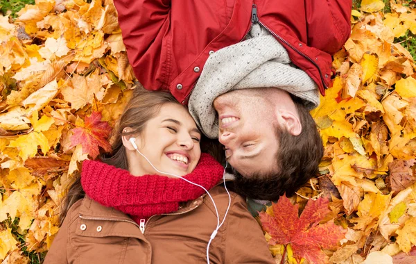 Close up of smiling couple lying in autumn park — Stock Photo, Image