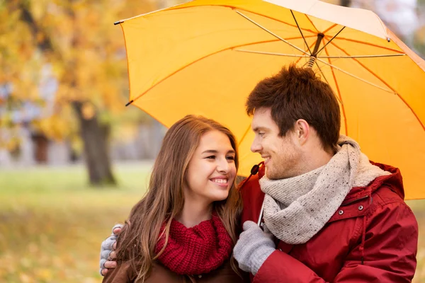 Pareja sonriente con paraguas en el parque de otoño — Foto de Stock