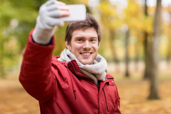 Człowiek biorąc selfie przez smartfon w jesienny park — Zdjęcie stockowe