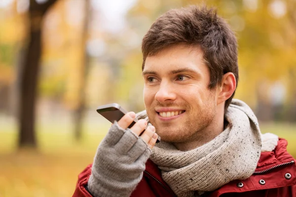 Mann nimmt Stimme auf Smartphone im Herbstpark auf — Stockfoto
