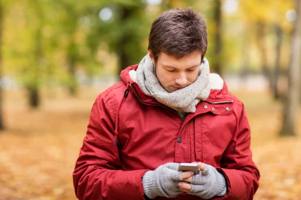 Młody człowiek z smartphone spaceru w parku jesień — Zdjęcie stockowe