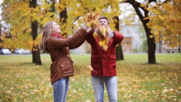 Happy young couple throwing autumn leaves in park — Stock Video