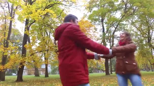 Счастливая молодая пара веселится в осеннем парке — стоковое видео