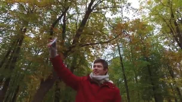 Mann mit Smartphone filmt im Herbstpark — Stockvideo