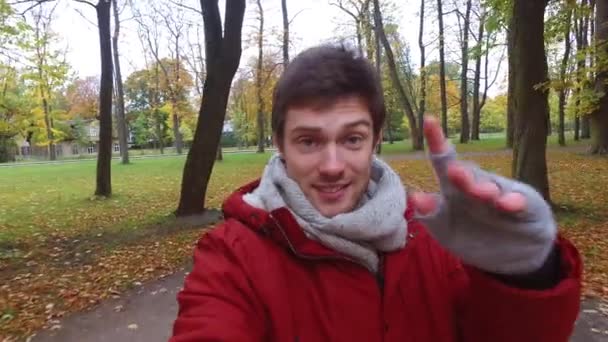 Мужчина со смартфоном снимает видео в осеннем парке — стоковое видео