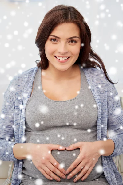 Happy pregnant woman making heart gesture at home — Stock Photo, Image