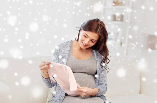 Happy woman holding baby girls bodysuit at home — Stock Photo, Image